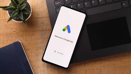 Mobile phone resting on laptop, displaying Google Adwords