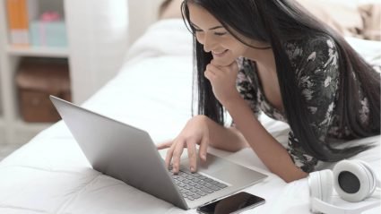 Woman laying on bed and shopping on a laptop