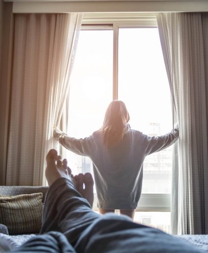 woman opening hotel room curtains