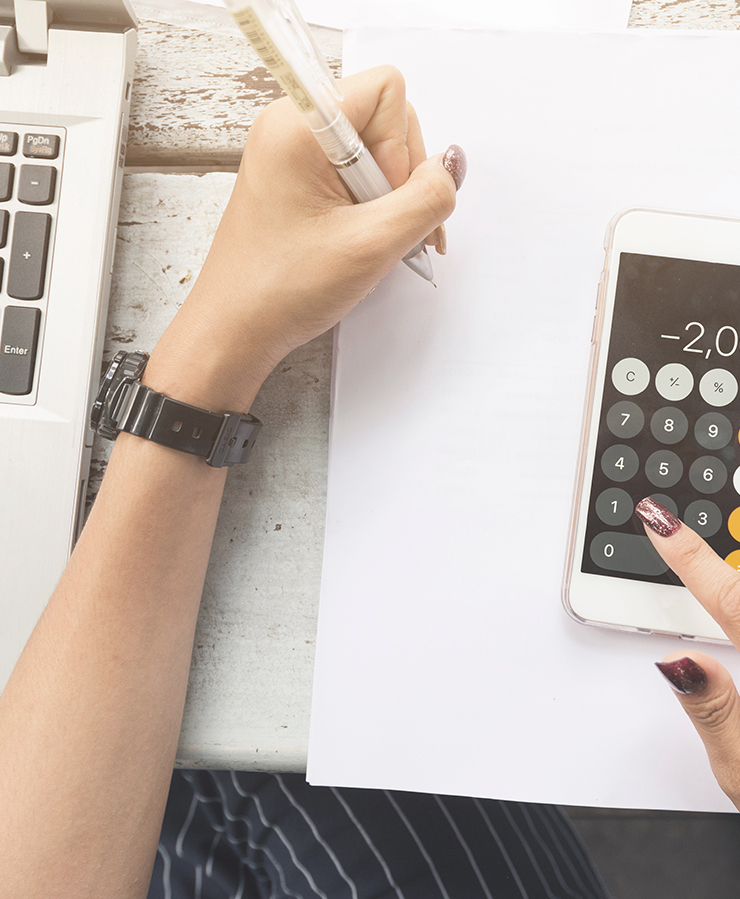 Woman writing notes with calculator