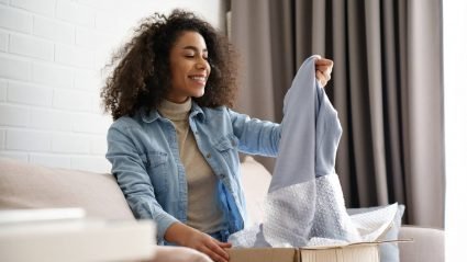 Woman removing clothes from a recently delivered purchase