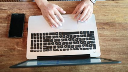 Overhead photo of hands placed on trackpad of laptop