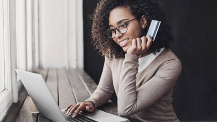 Woman using a laptop and holding a credit card