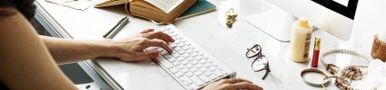 female hands typing on white keyboard on white desk