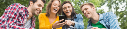 group of young people laughing and pointing at phone