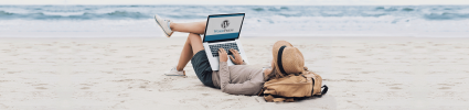 woman in hat lying on beach with Wordpress logo on laptop