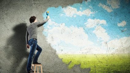 man painting a new mural over a plain wall