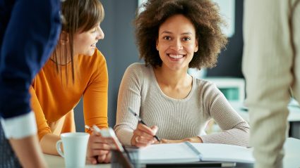 Young woman sitting at desk with coworkers