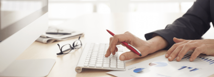 Typing on keyboard with data and charts on the desk