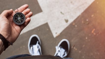 Person holding compass with arrow pointing forward