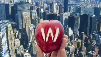 Hand holding apple with "W" carved into the skin