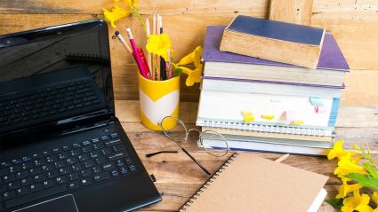 Student desktop with computer, books and spring flowers