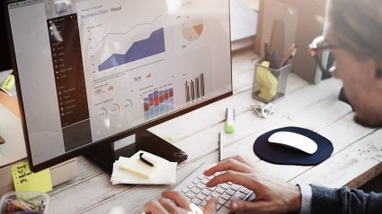 man sitting at desk looking at analytics on computer screen