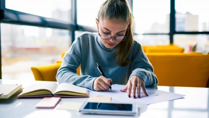 young woman sitting at table writing and planning budget