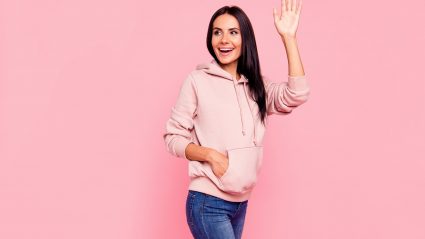 woman in pink sweatshirt waving bye on pink background