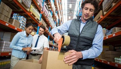 man in warehouse taping up box