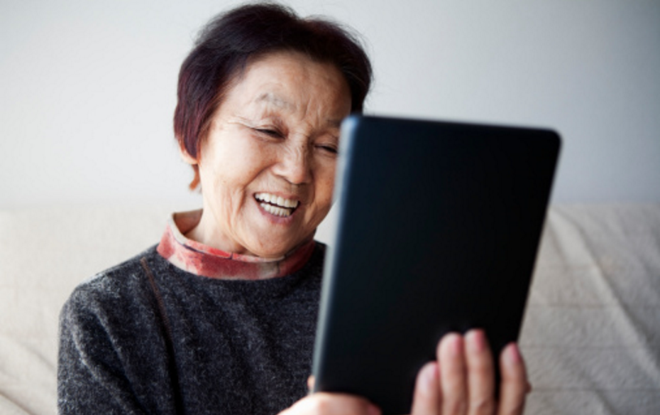 senior citizen woman smiling and looking at ipad