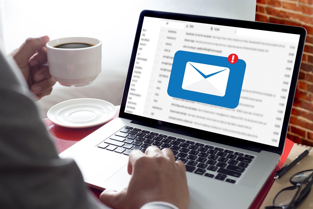 person drinking coffee with new email alert on laptop