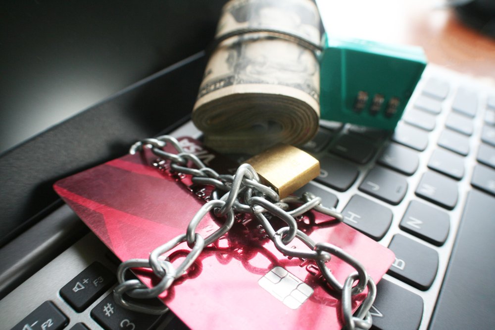 chained credit card and roll of cash on top of keyboard