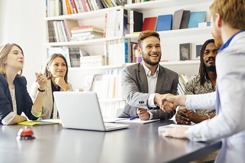 group of people in an office setting two men shaking hands