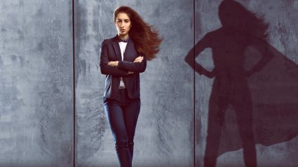 Woman in suit with reflection of wearing a cape in her shadow