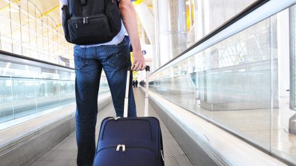 Man in airport wheeling luggage