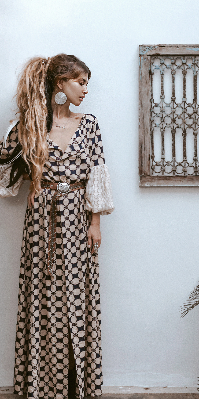 woman in bohemian clothing posing against wall