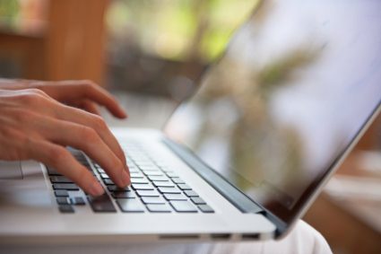 close up of hands typing on laptop keyboard