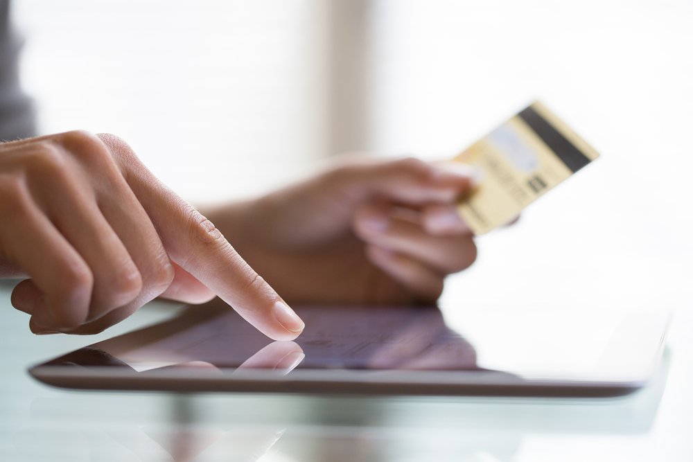 closeup on finger pointing to ipad and other hand holding credit card