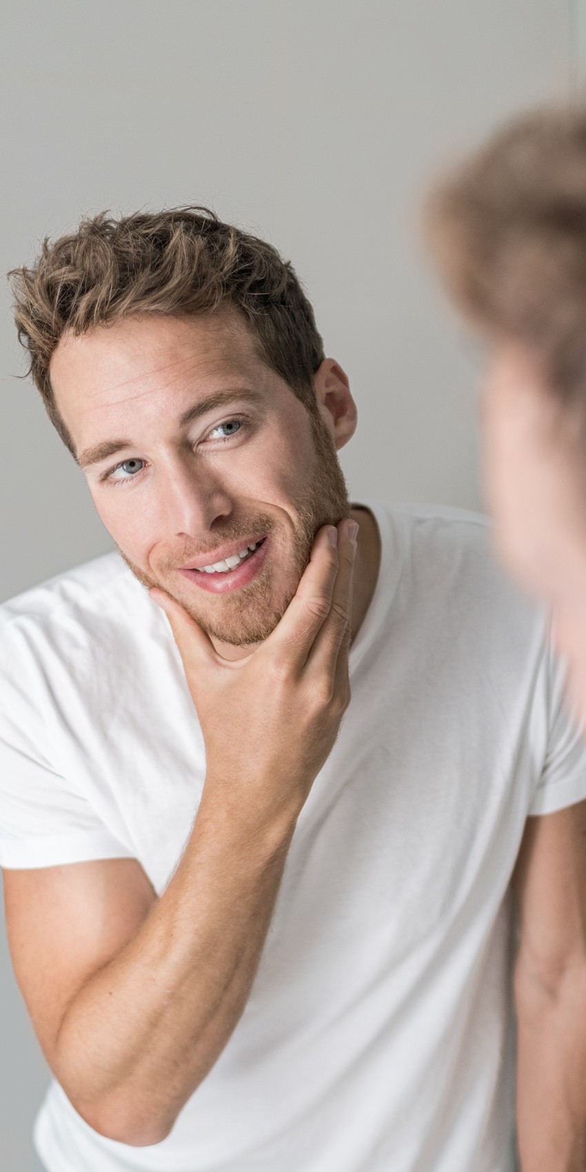 man looking at clear skin in mirror