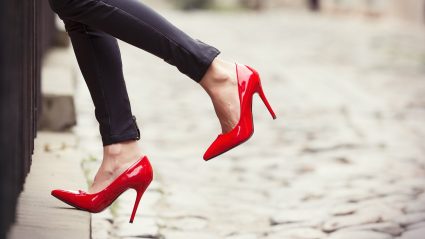 Woman walking on sidewalk with red high heels