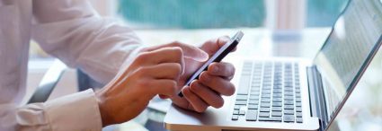 Man sitting in front of computer with local SEO on his phone