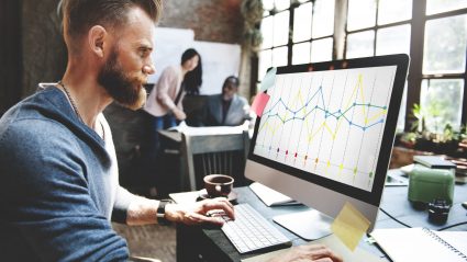 man in office setting looking at graphs on computer