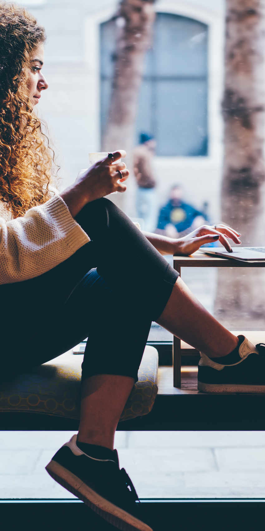 woman sitting in window on laptop