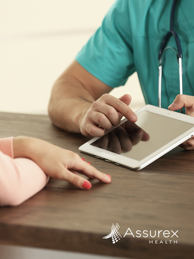 Doctor sitting with patient looking at tablet