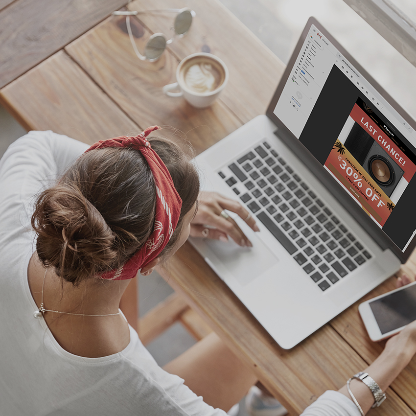 woman in cafe looking at klipsch email on laptop