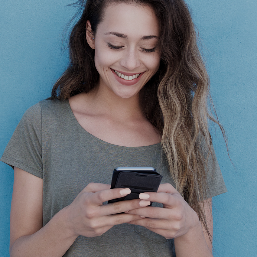 woman looking at phone standing against blue wall