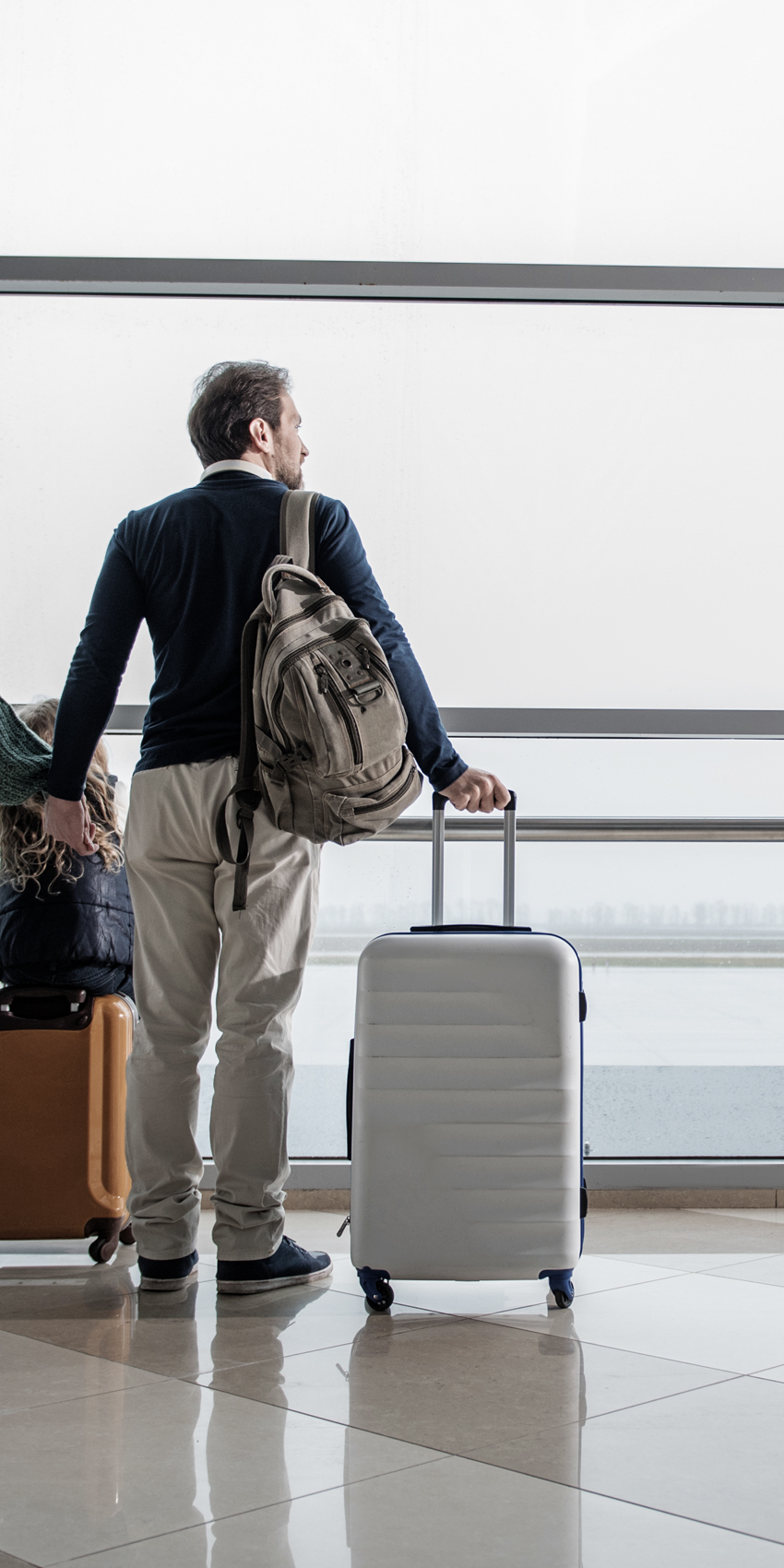 couple at airport with luggage looking out window