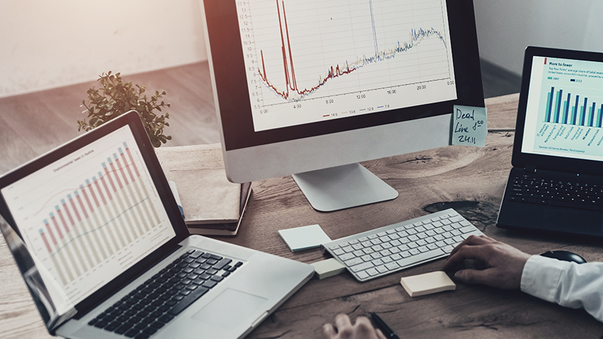 man sitting at desk with multiple screens and graphs
