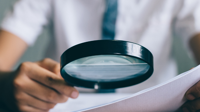 looking at paper with magnifying glass