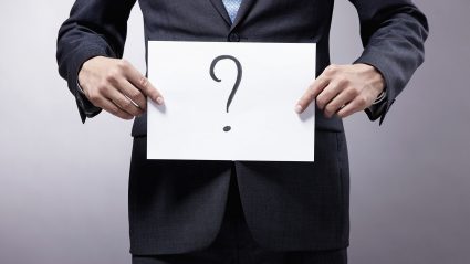 Executive holding sign with questions mark
