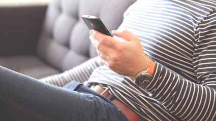 Man sitting on couch and using a mobile phone