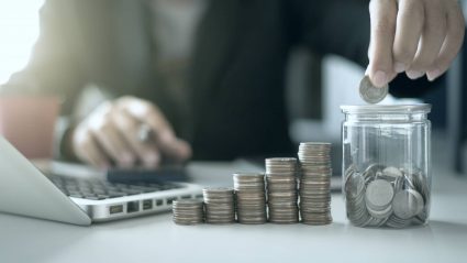 Person counting profits in increasing stacks of coins