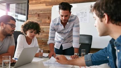 Group of four creative professionals meeting in a modern office space