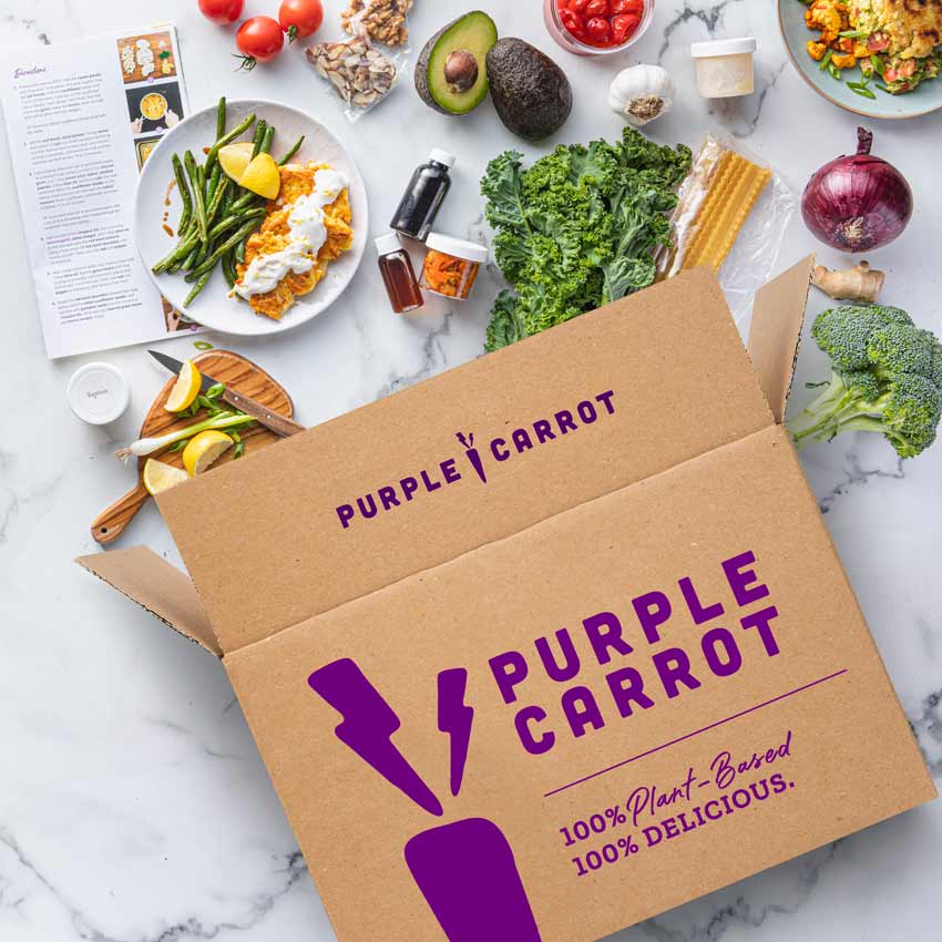 Overhead shot of Purple Carrot box with various vegan ingredients arranged on a marble countertop