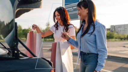 Two women putting shopping bags in a trunk