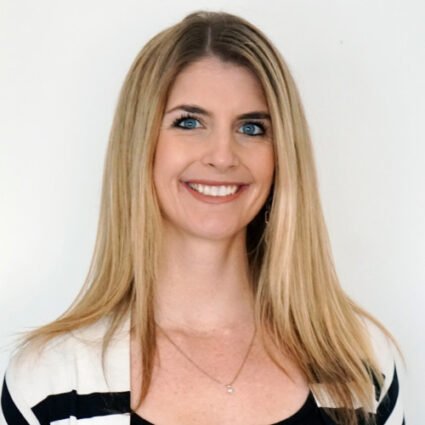 A woman with long straight blonde hair, blue eyes, and a striped top smiles at the camera against a plain white background.