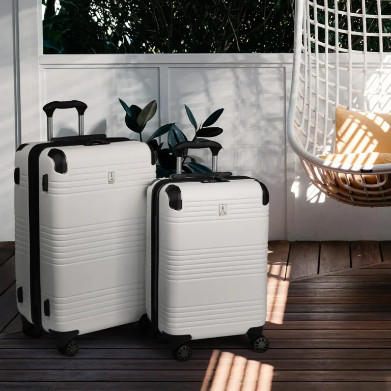 Two white hard-shell suitcases with black trim on a wooden deck next to a potted plant and a white hanging chair with a yellow cushion.