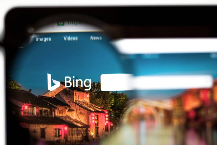 A computer screen shows the Bing search engine homepage, viewed through a magnifying glass.
