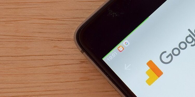 A smartphone on a wooden surface displays the Google Analytics app page in an app store.